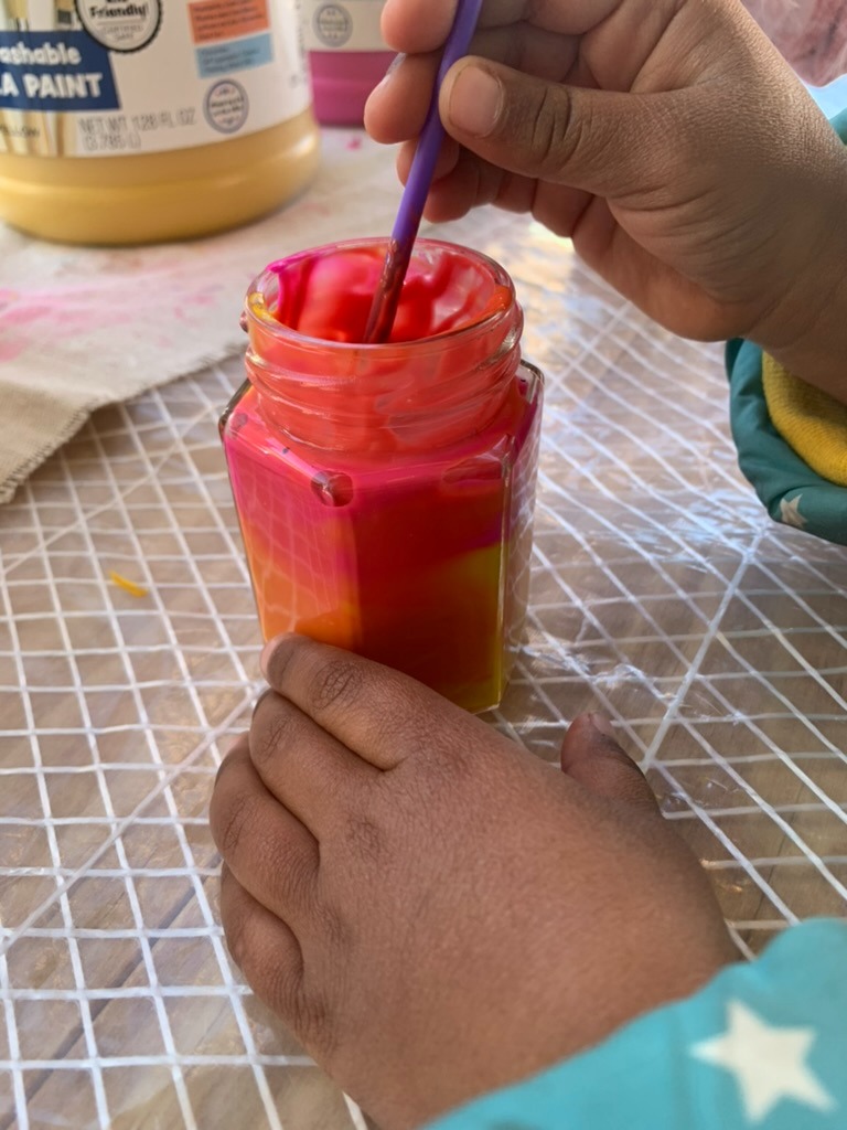 Child mixing red and yellow to unlock and discover new pigment