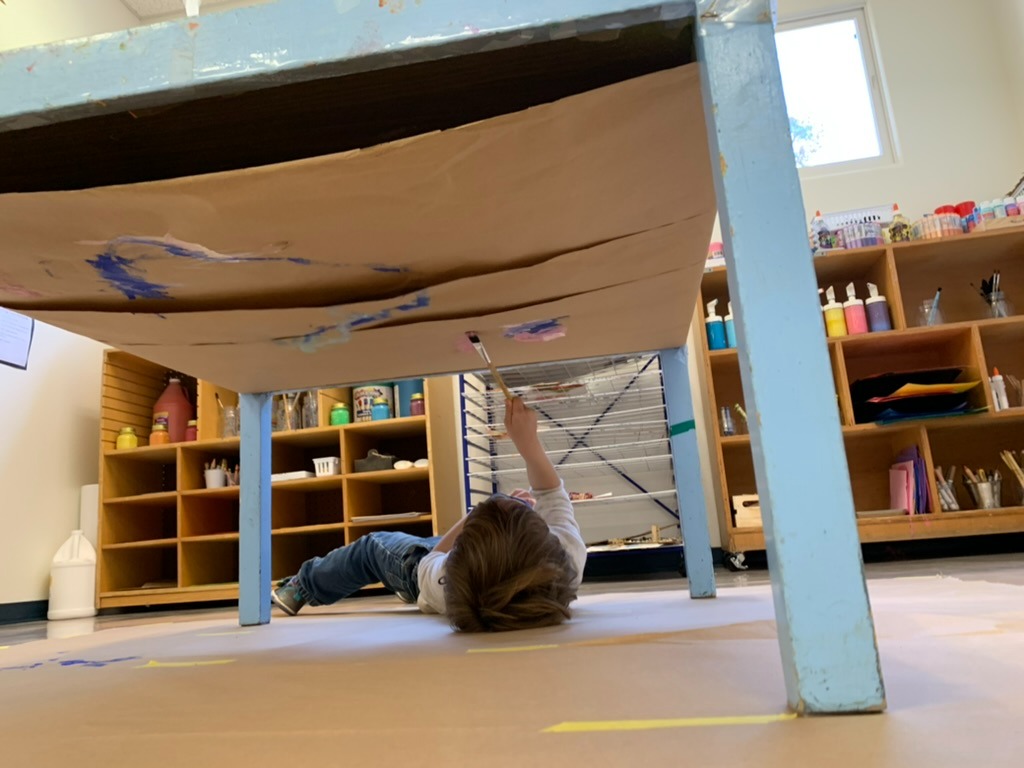 Child exploring art in a different perspective, under the table